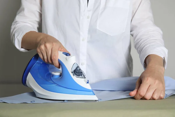 Woman ironing clean shirt on board, closeup