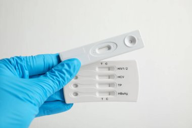 Doktorun elinde iki adet tek kullanımlık hepatit testi var. Beyaz arka plan, yakın plan.