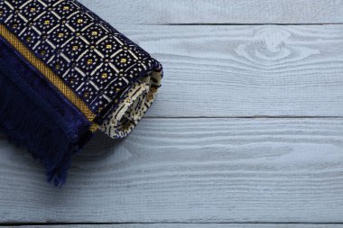 Muslim prayer rug on grey wooden table, above view. Space for text