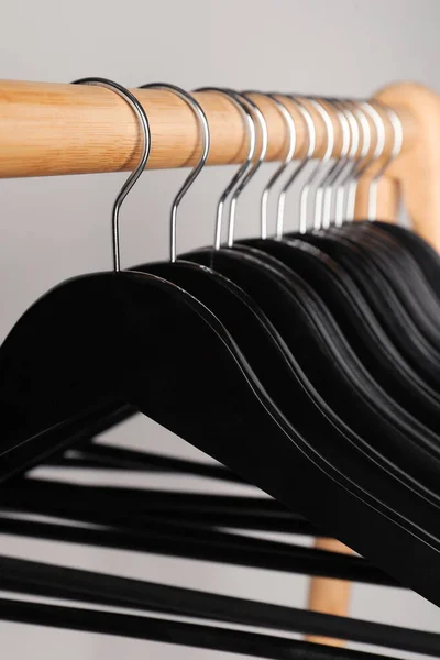 Black Clothes Hangers Wooden Rail Light Grey Background Closeup — Fotografia de Stock