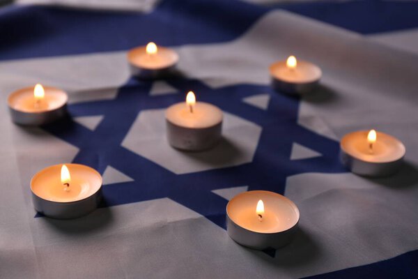 Burning candles on flag of Israel. Holocaust memory day