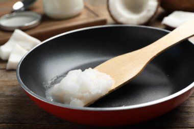 Tahta masada hindistan cevizi yağı ve ahşap spatula ile kızartma tavası. Sağlıklı yemek.