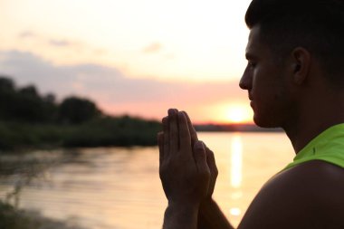 Adam gün batımında nehrin kenarında meditasyon yapıyor. Metin için boşluk