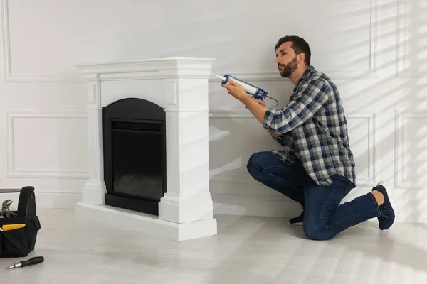 Man Sealing Electric Fireplace Caulk White Wall Room — Stockfoto