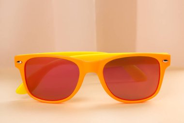 Bej arka planda yeni şık güneş gözlüğü, yakın plan.