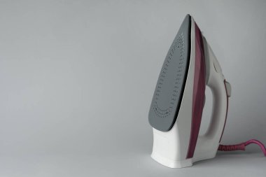 Açık gri arka planda modern bir ütü, metin için boşluk. Ev aletleri