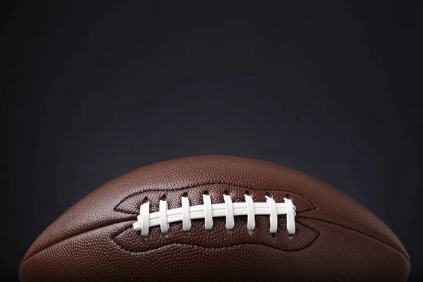 American football ball on black background, closeup. Space for text