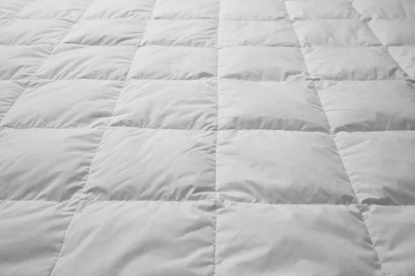 Soft quilted blanket as background, closeup view