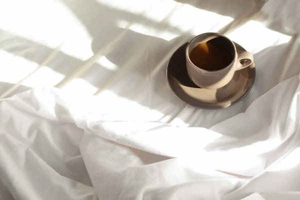 Cup of aromatic coffee on bed in morning, space for text