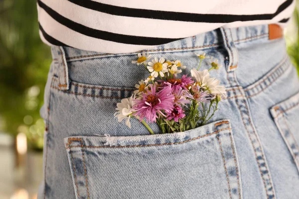 在户外牛仔裤后兜里放着美丽娇嫩的花朵的女人 特写镜头 — 图库照片