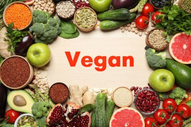 Kelime vegan ve yeni ürünler ahşap arka planda, düz yatıyordu