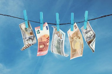 Money laundering. Banknotes hanging on clothesline against blue sky