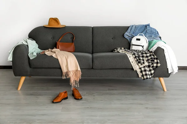 Messy pile of clothes on sofa and shoes in living room