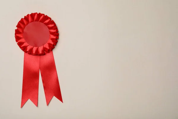 Red award ribbon on beige background, top view. Space for text