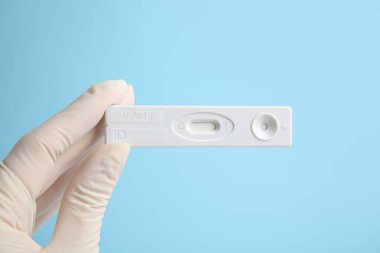 Açık mavi arka planda hepatit için tek kullanımlık ekspres test tutan doktor, yakın plan