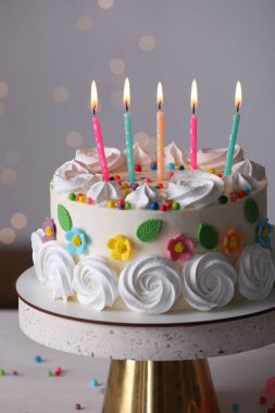 Bulanık festival ışıklarına karşı parti dekoruyla nefis bir doğum günü pastası, yakın plan.