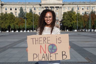 African American young woman with poster protesting against climate change on city street