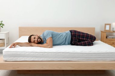 Happy man on bed with comfortable mattress at home