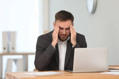 Tired man with red eyes at workplace in office