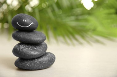 Beyaz masaya çizilmiş gülen yüzlü taşlar yığını, yazı için yer. Uyum içinde ol ve hayatın tadını çıkar.