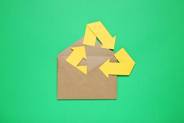 Open envelope and recycling symbol on green background, top view