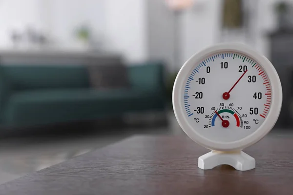 Round mechanical hygrometer on wooden table in room. Space for text