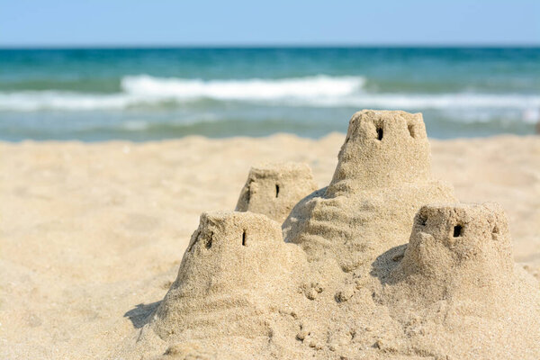 Beach with sand castle near sea on sunny day. Space for text