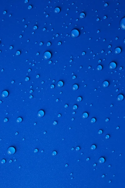 Water drops on blue background, top view