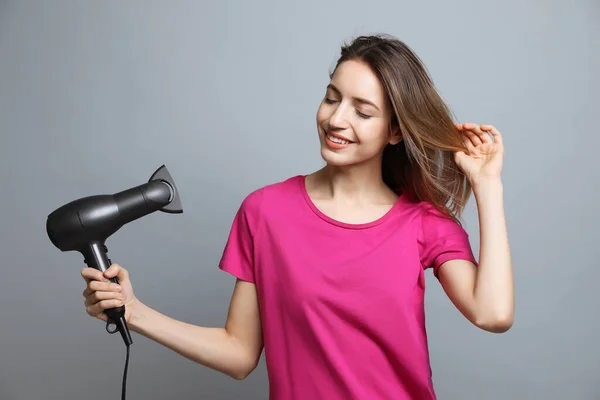 Mooie Jonge Vrouw Met Behulp Van Haardroger Grijze Achtergrond — Stockfoto