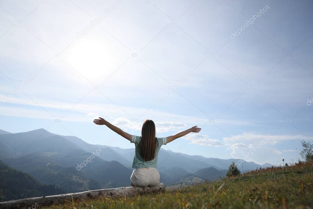 Young woman in peaceful mountains, back view. Feeling freedom