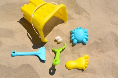 Parlak plastik kova, kumda tırmık ve kürek. Plaj oyuncakları
