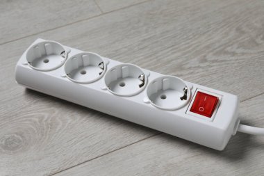 Power strip on wooden floor, closeup. Electrician's equipment