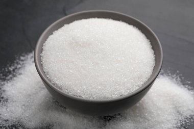 Granulated sugar on black table, closeup view