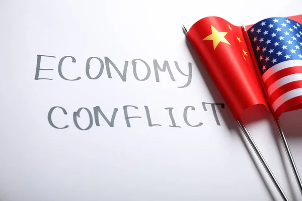 USA and China flags near words ECONOMY CONFLICT on white background