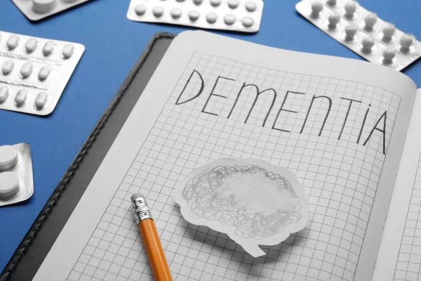 Notebook Word Dementia Brain Cutout Pencil Pills Blue Background Closeup — Stockfoto