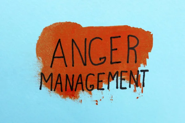 Phrase Anger Management written on light blue background with color paint