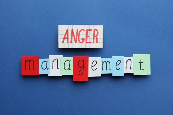 Sheets of paper with words Anger Management on blue background, flat lay