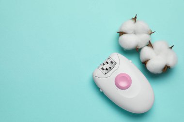 Turkuaz arka planda modern epilatör ve pofuduk pamuk çiçekleri, düz yatak. Metin için boşluk