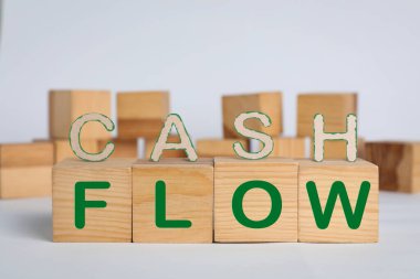 Harflerden ve arka planda tahta küplerden oluşan Cash Flow deyimi