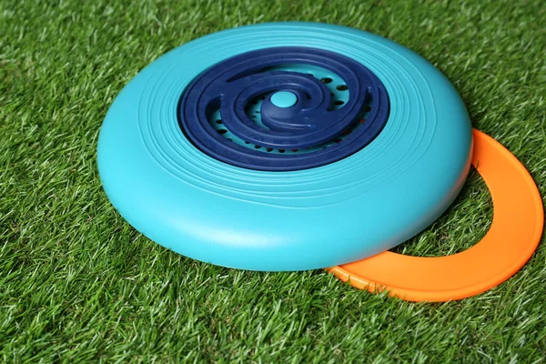 Plastic frisbee disk and ring on green grass, closeup