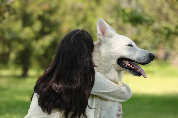 年轻女子抱着她的白色瑞士牧羊犬在公园里 后视镜 — 图库照片