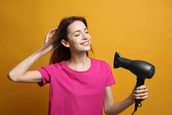 Mooie Jonge Vrouw Met Behulp Van Haardroger Gele Achtergrond — Stockfoto