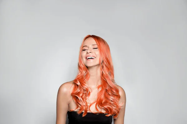 Beautiful woman with long orange hair on light background