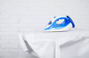 Modern demir ve temiz gömlek beyaz tuğla duvarın yanında, metin için yer var.