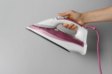 Açık gri arka planda modern demiri tutan kadın, yakın plan.