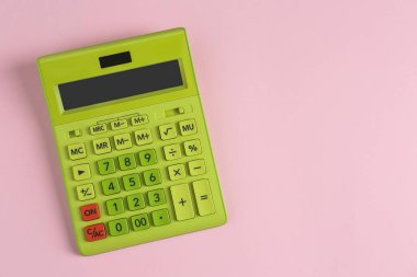 Pembe arka planda yeşil hesap makinesi, üst manzara. Metin için boşluk