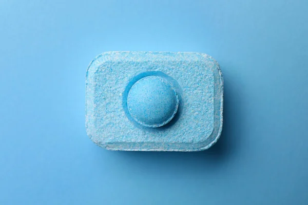 Water softener tablet on light blue background, top view