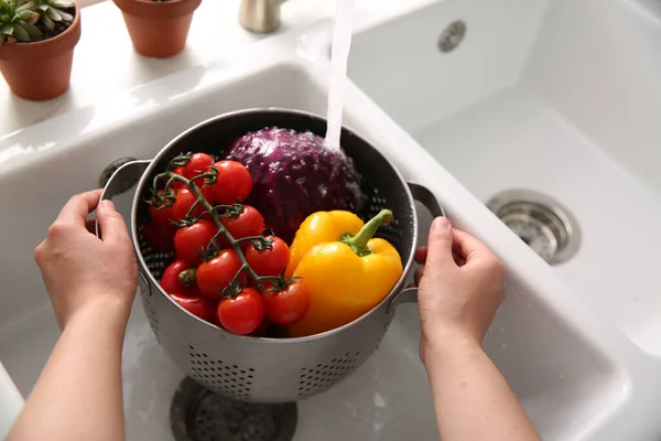 Woman washing fresh vegetables in kitchen sink, closeup