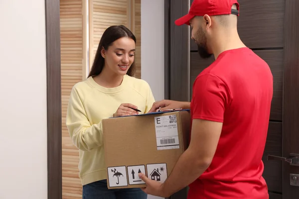 Woman Signing Delivered Parcel Home — Stockfoto