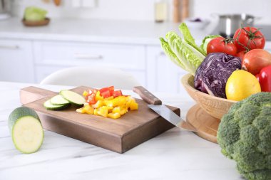 Mutfaktaki beyaz mermer masada farklı çiğ sebzeler.